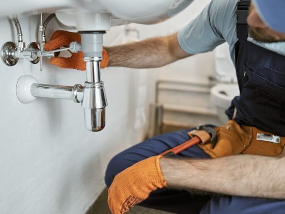 Plombier réparant un siphon de lavabo